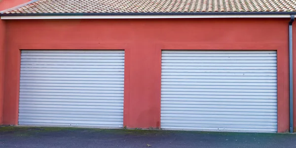 red industrial building facade closed two grey roller shutter gate