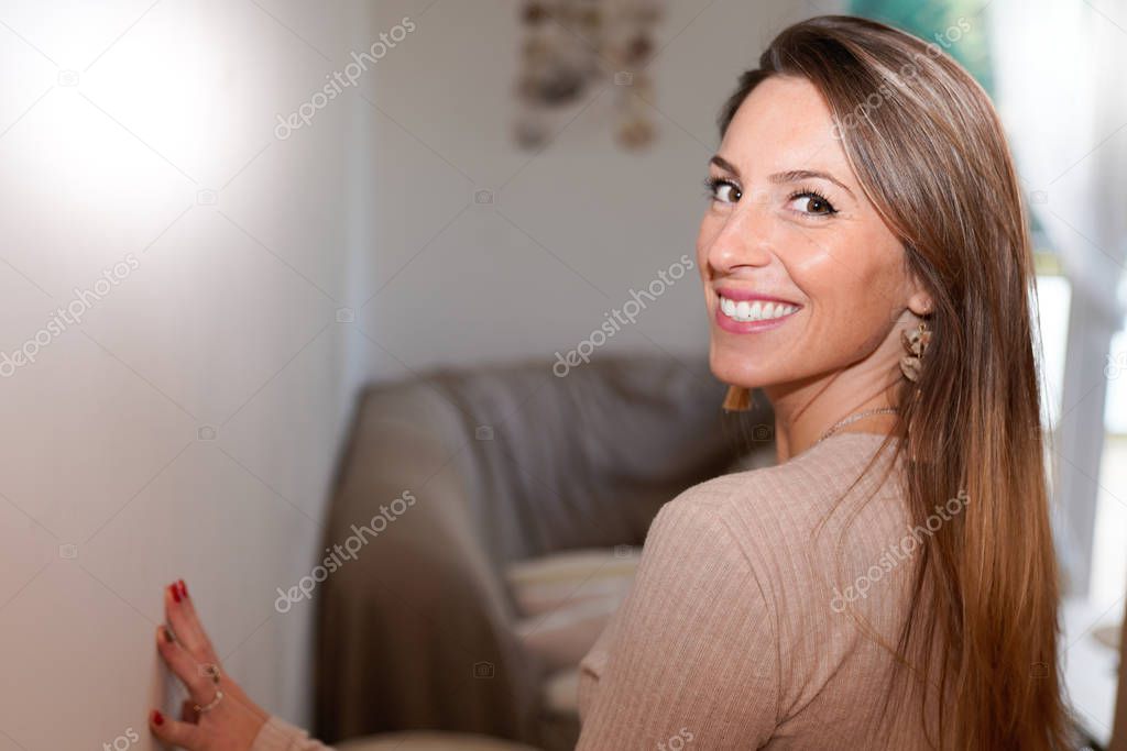 Portrait of happy beautiful blonde woman at home living room interior house