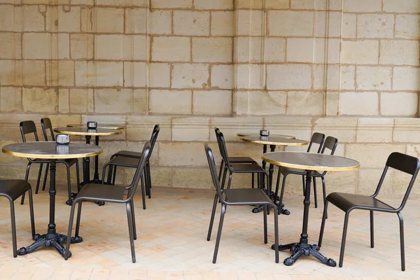 Empty retro tables and chairs on stone building outdoor coffee cafe terrace in Bordeaux France