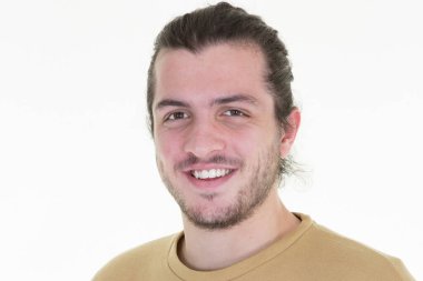 Genç, uzun saçlı, beyaz arka planda yalnız gülen, neşeli yüzlü bir adam.