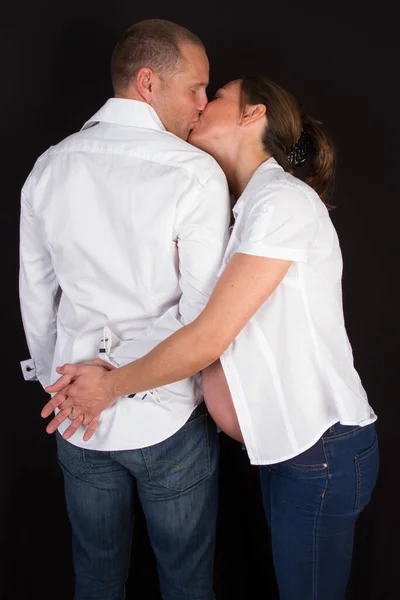 年轻夫妇期待着宝宝站在一起亲吻在屋里回望爱情 — 图库照片