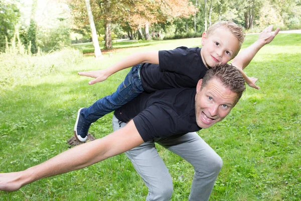 Pohledný Otec Roztomilý Syn Hrát Zábava Venku Piggyback Letadlo Zelené — Stock fotografie