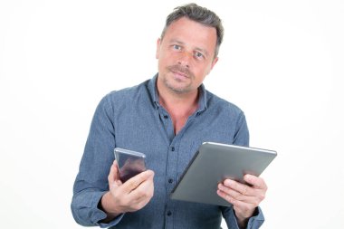 Beyaz arka planda akıllı telefon ve bilgisayar tableti tutan yakışıklı adam portresi.