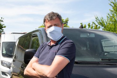 Koruyucu tıbbi maskeli bir adam ön vagonda karantina covid-19 'daki koronavirüs enfeksiyonunu koruyor.