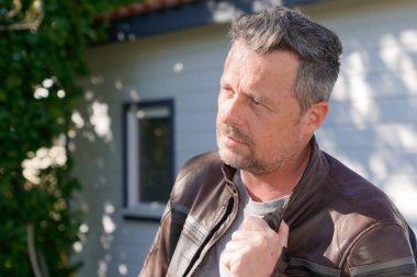 Motosikletli yakışıklı adam yaz günü yan bakıyor.