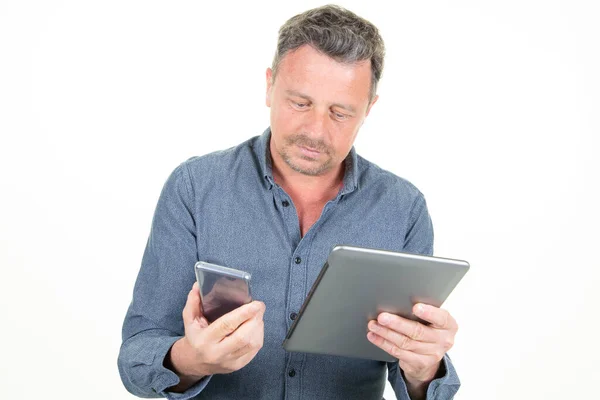 Poważny Pracownik Pomocą Tabletu Patrząc Telefon Komórkowy Izolowany Białym Tle — Zdjęcie stockowe