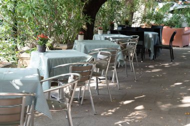 Gölge kafe masası ve barın dışındaki terasta sandalyeler.