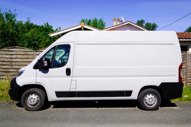 Beyaz teslimat kamyonu caddede karavan görüntüsü oluşturuyor.