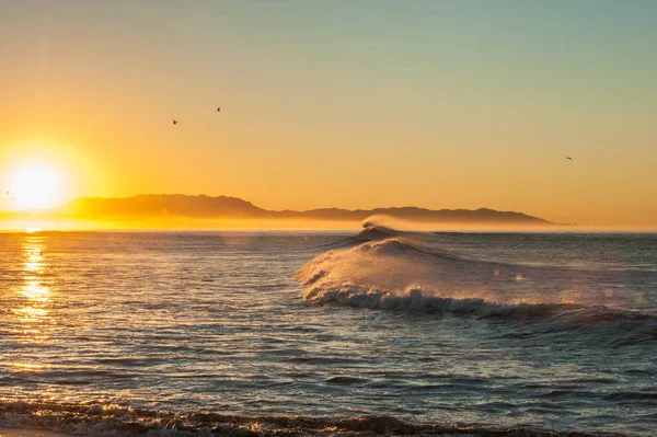 Şişmiş dalgalar deniz arkasında yükselen güneş Rüzgar.