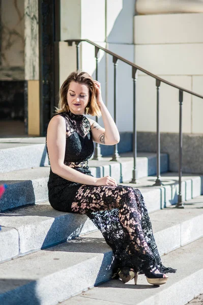 Mujer Joven Vestido Encaje Negro Ajustando Cabello Mientras Está Sentada — Foto de Stock