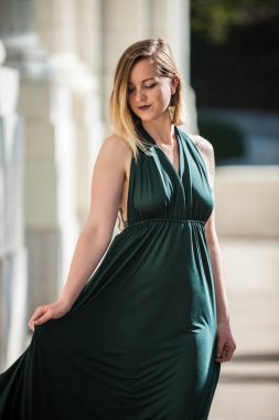 Zümrüt yeşil yular en iyi elbise rüya gibi sarışın model beton yürüyüş güzel görünüyor.