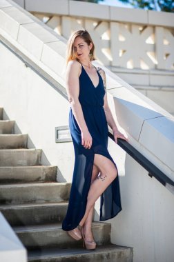 Merdiven azalan alternatif modeli tarafından giyilen kolsuz mavi gece elbisesi.