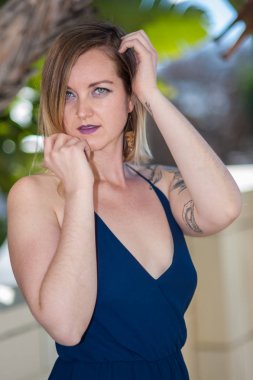 Yüzünü elleriyle çerçeveleme mavi saf elbiseli adil tenli sarışın kadın.