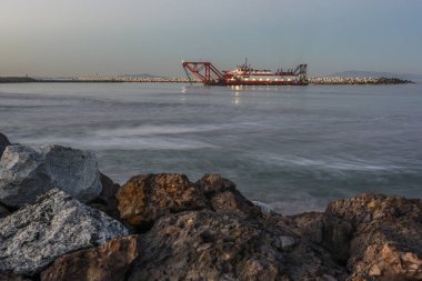 Tekneyi kıyıya yakın şafak çalışma tarama ön plan sörf büyük kayalar ile okyanus su.