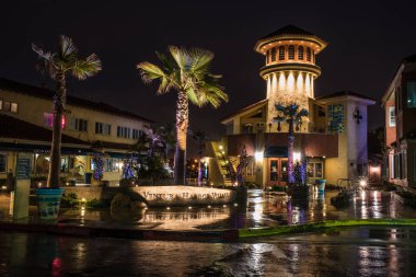 Ventura Harbor Village in California, United states wet and reflecting morning spot lights of shopping area in the predawn hours of March, 2018. clipart