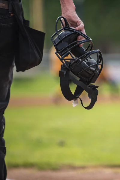 棒球裁判员拿着面具在手 他在田野上看着打个电话 — 图库照片