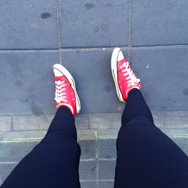 Portre siyah kot ve kat veya zemin arka plan kırmızı spor ayakkabılar giyiyor bacak