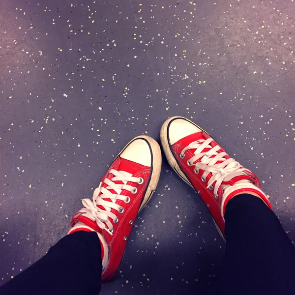 Крупним планом ноги носити чорні джинси і червоний кросівки на підлозі або землі фону — стокове фото