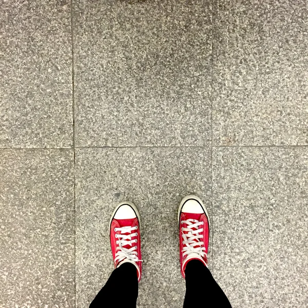Κόκκινα αθλητικά παπούτσια στα πόδια κορίτσι σε έδαφος φόντο — Φωτογραφία Αρχείου