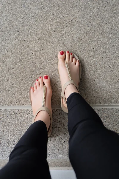 Pieds féminins portant des pantoufles ou un clou rouge extérieur flip-flop — Photo