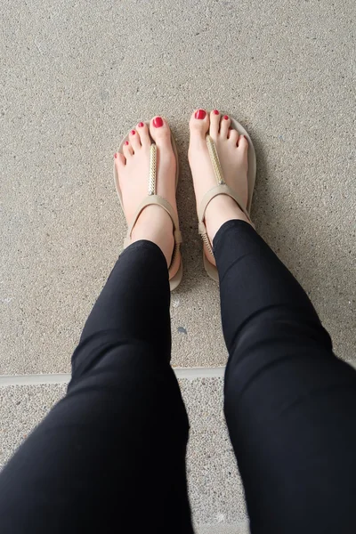 Pés femininos usando chinelos ou flip-flop unhas vermelhas ao ar livre — Fotografia de Stock
