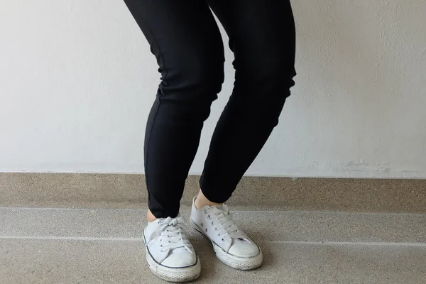 White sneakers on girl legs on ground background — Stock Photo, Image