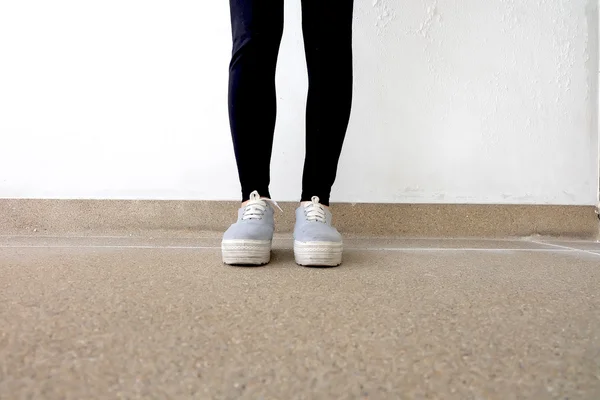 Junge Modefrau in Jeans und Turnschuhen auf dem Boden — Stockfoto