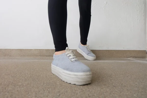 Jovens pernas de mulher de moda em jeans e tênis no chão — Fotografia de Stock