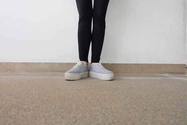 Piernas de mujer de moda joven en jeans y zapatillas de deporte en el suelo —  Fotos de Stock
