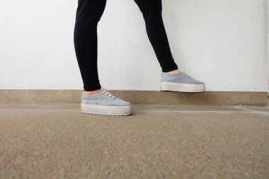 Genç kadının bacakları kot pantolon ve spor ayakkabı katta moda 