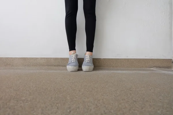 Genç kadının bacakları kot pantolon ve spor ayakkabı katta moda — Stok fotoğraf