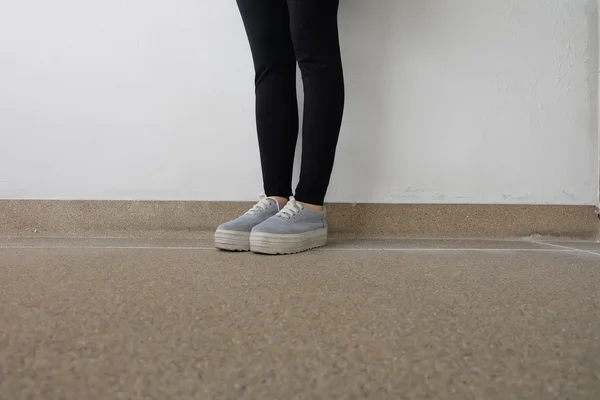 Νέοι μόδας στα πόδια της γυναίκας τζιν και αθλητικά παπούτσια στο πάτωμα — Φωτογραφία Αρχείου