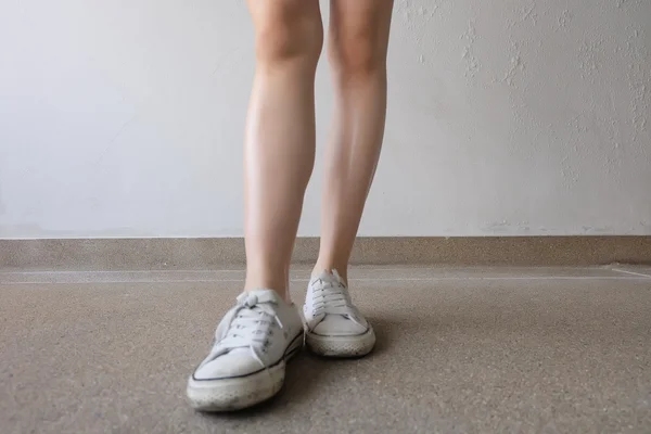 Scarpe da ginnastica bianche sulle gambe della ragazza a terra — Foto Stock