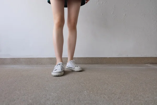 Zapatillas blancas en las piernas de la muchacha en el suelo — Foto de Stock