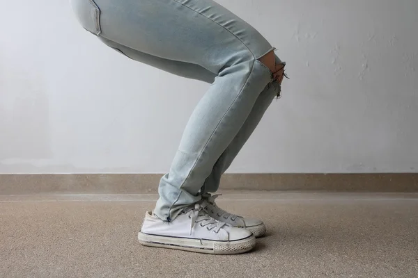 Młoda Moda Woman nogi w niebieskie dżinsy i białe sneakers na podłodze — Zdjęcie stockowe