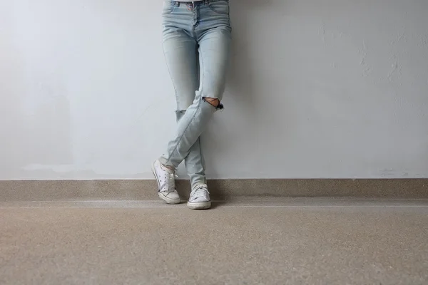 Pernas de mulher de moda jovem em calças de ganga azuis e tênis brancos no chão — Fotografia de Stock