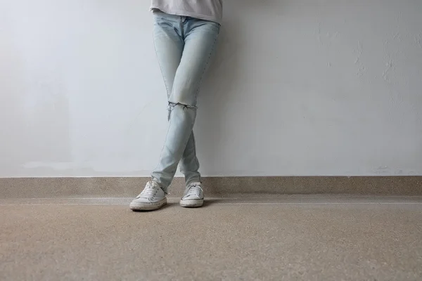 Young Fashion Woman's Legs in Blue Jeans and White Sneakers on Floor — Stock Photo, Image