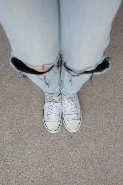 Young Fashion Woman's Legs in Blue Jeans and White Sneakers on Floor — Stock Photo, Image