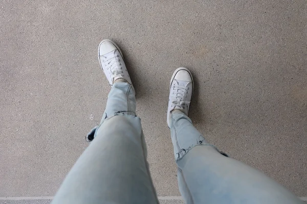 Mavi kot Genç moda kadın bacaklar ve katta beyaz Sneakers — Stok fotoğraf