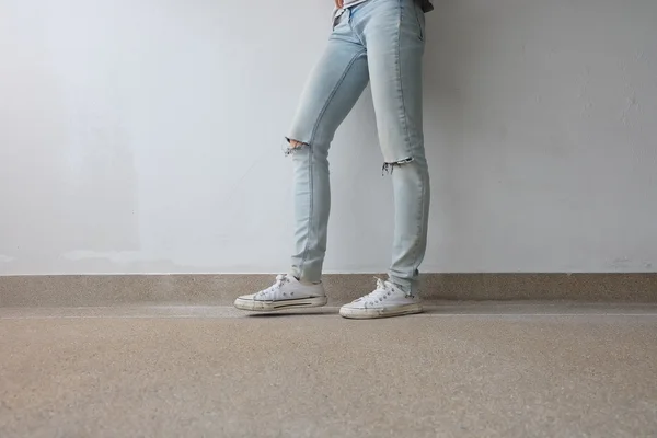 Young Fashion Woman's Legs in Blue Jeans and White Sneakers on Floor — Stock Photo, Image