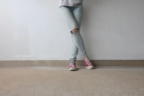 Young Fashion Woman's Legs in Blue Jeans and Red Sneakers on Floor — Stock Photo, Image