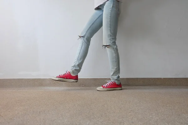 Young Fashion Woman's Legs in Blue Jeans and Red Sneakers on Floor — Stock Photo, Image