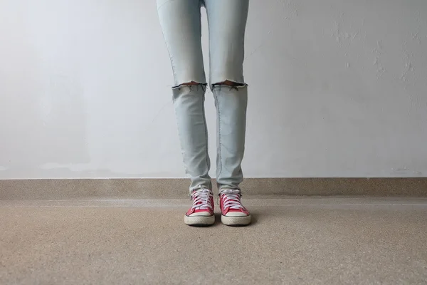 Junge Modefrau in blauen Jeans und roten Turnschuhen auf dem Boden — Stockfoto