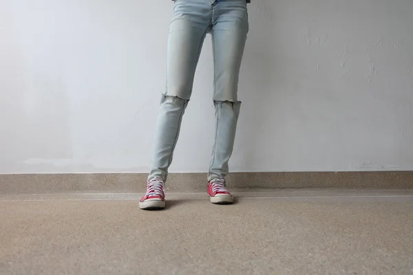 Unga mode kvinnans ben i blå jeans och röda sneakers på golvet — Stockfoto