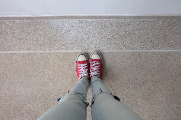 Young Fashion Woman's Legs in Blue Jeans and Red Sneakers on Floor — Stock Photo, Image