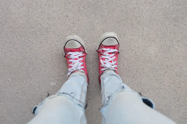 Молода мода жінка ноги в синіх джинсах і червоні кросівки на підлозі — стокове фото