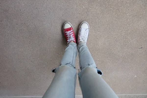 Young Fashion Woman's Legs in Blue Jeans and White, Red Sneakers on Floor — Stock Photo, Image