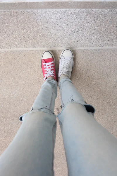 Pernas de mulher de moda jovem em azul jeans e branco, tênis vermelho no chão — Fotografia de Stock