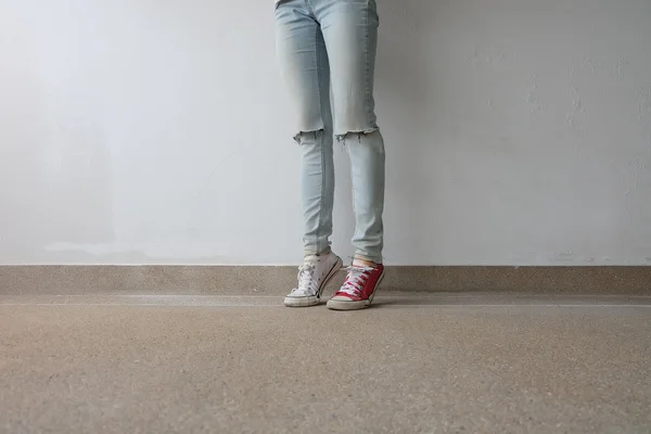 Young Fashion Woman's Legs in Blue Jeans and White, Red Sneakers on Floor — Stock Photo, Image