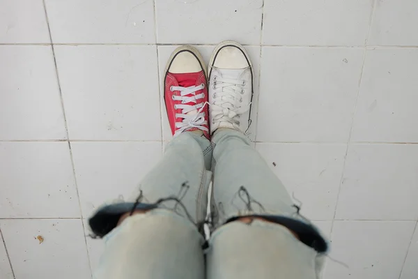 Young Fashion Woman's Legs in Blue Jeans and White, Red Sneakers on Floor — Stock Photo, Image